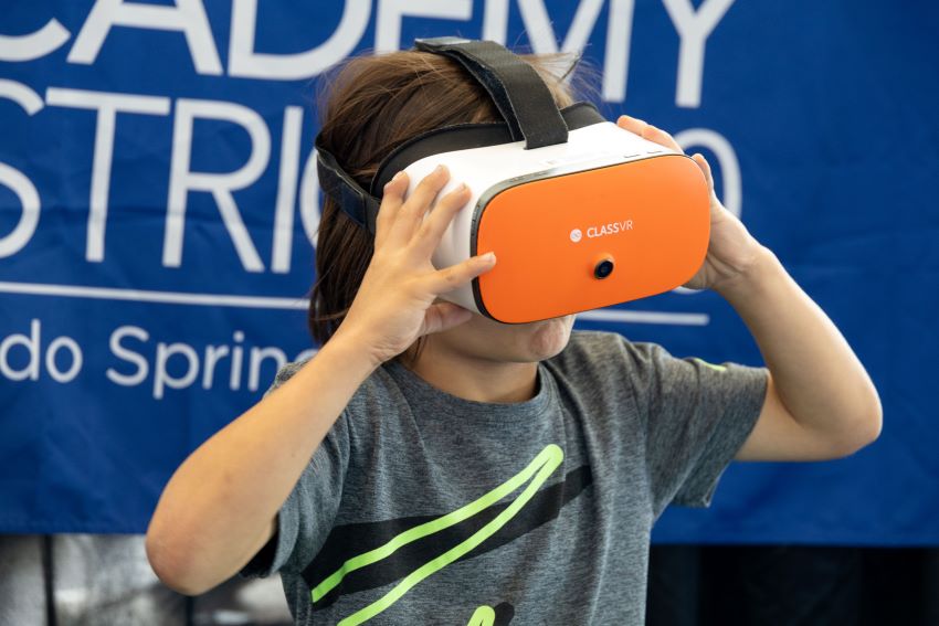 Boy holding a VR headset on his face.