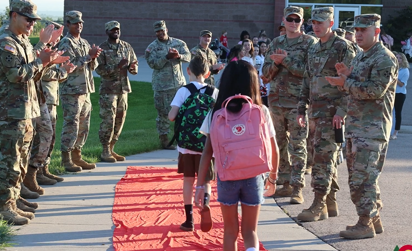 Students walk into school while being applauded by soldiers from Fort Carson Army post.