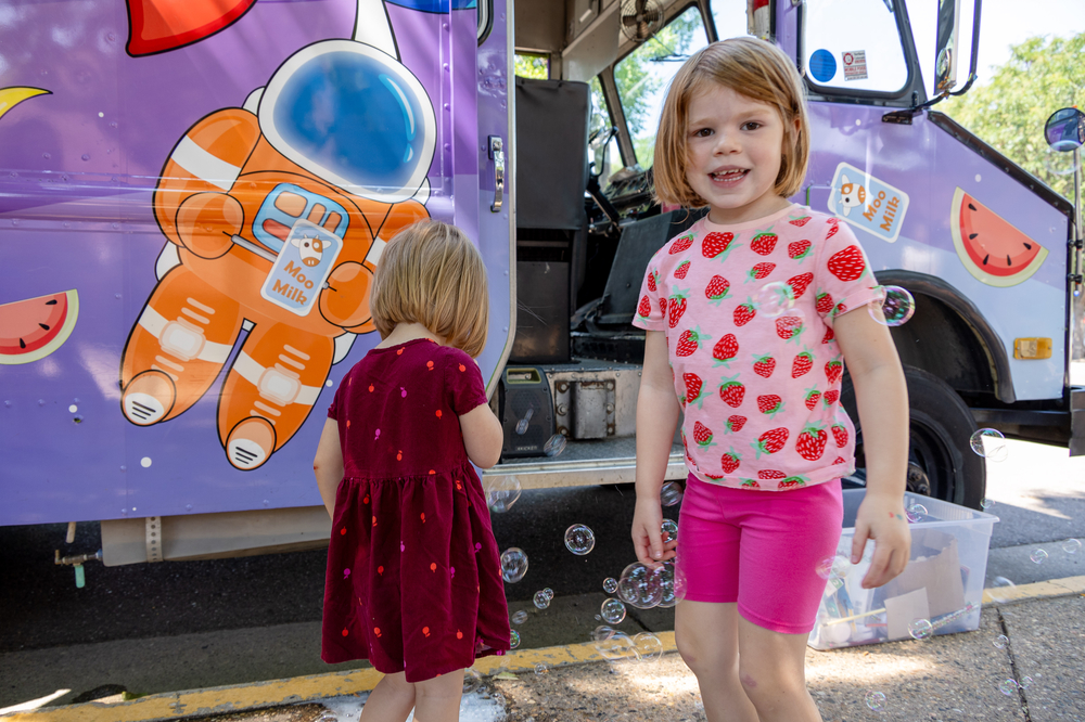 A child smiles in front of a food truck.