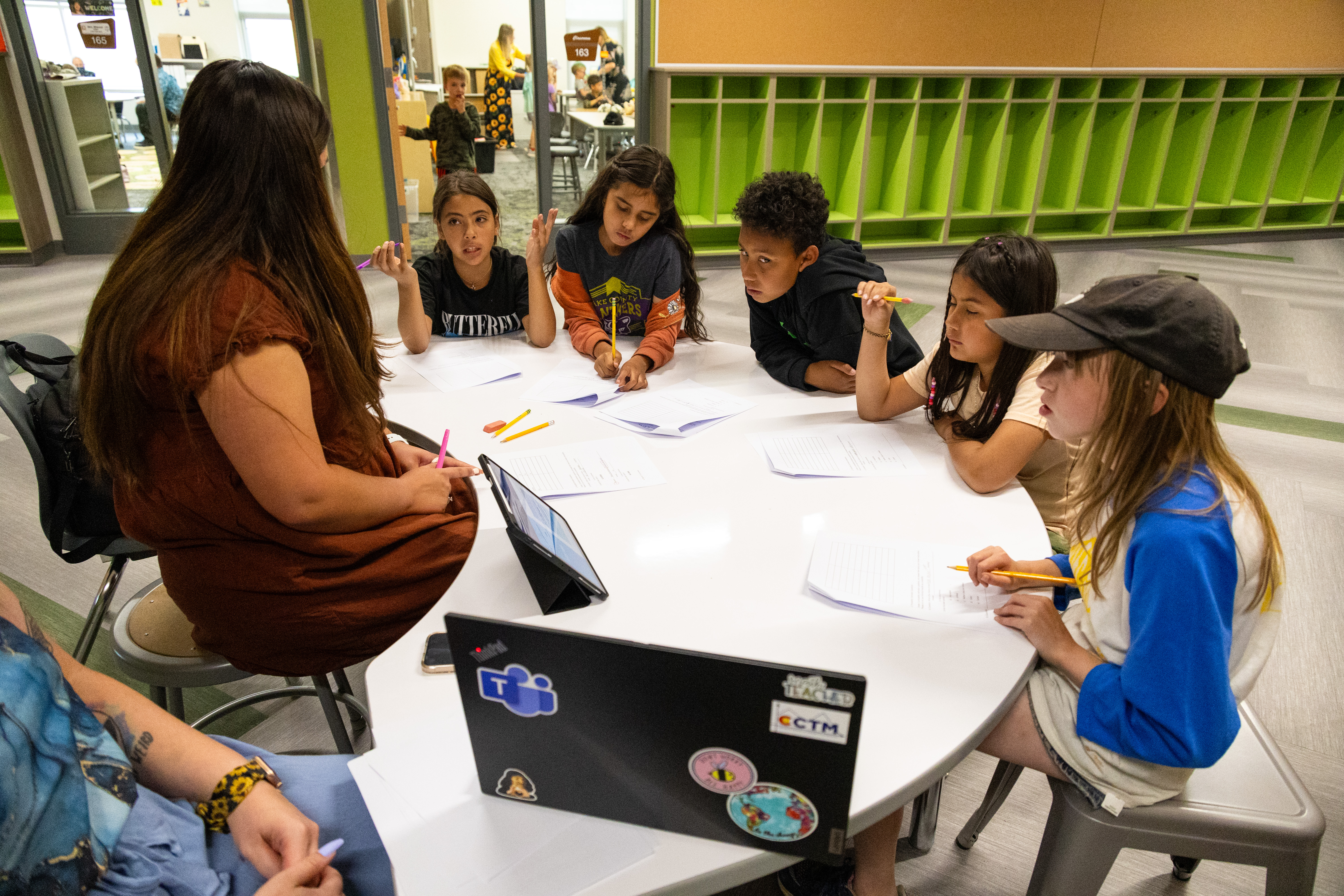 Students sitting at a table in a school hallway. 